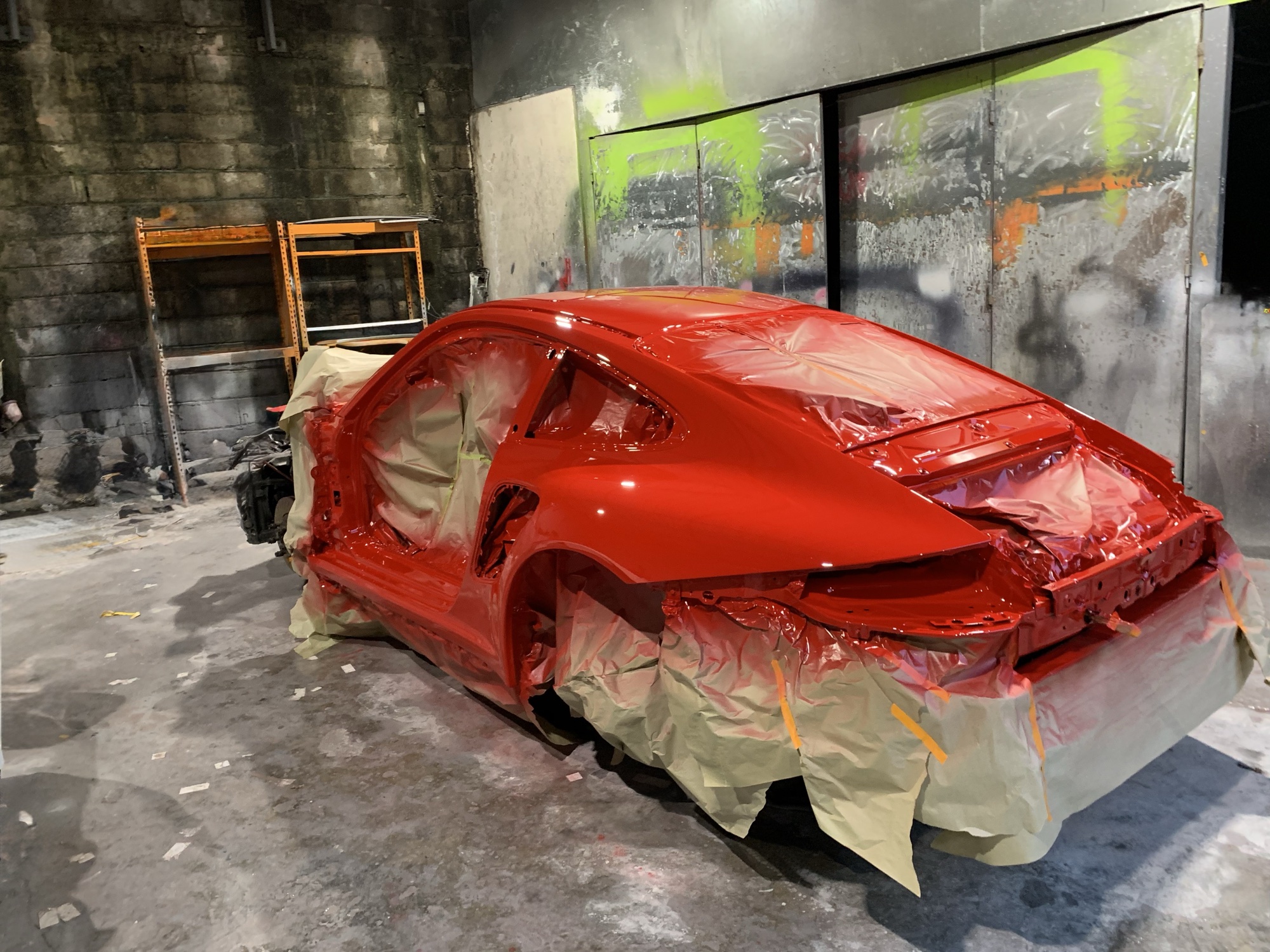 Freshly painted red Porsche 911 shell masked in the 9Eleven paint booth